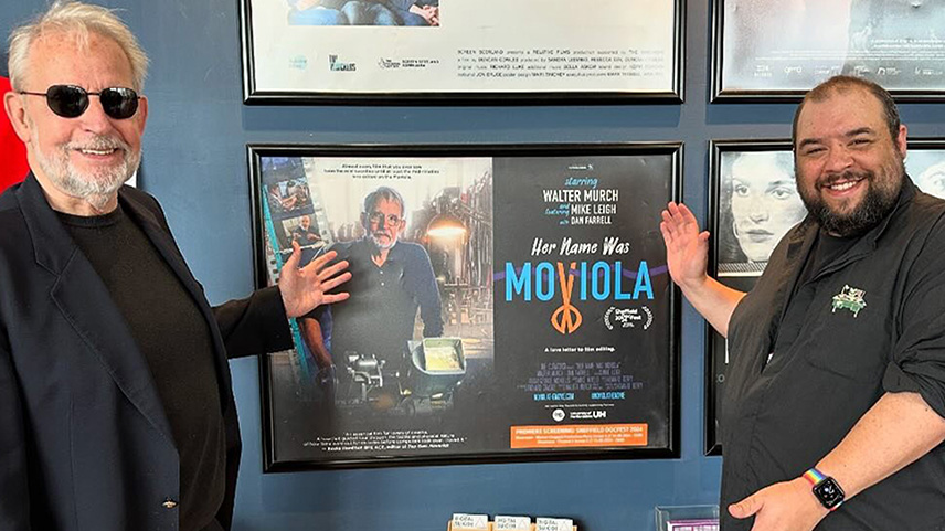 Two men pointing at a display advertising a new film