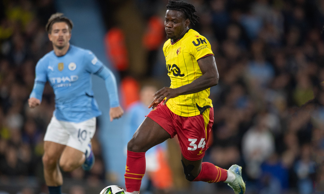 Watford football players near a ball with a Manchester City player in the background