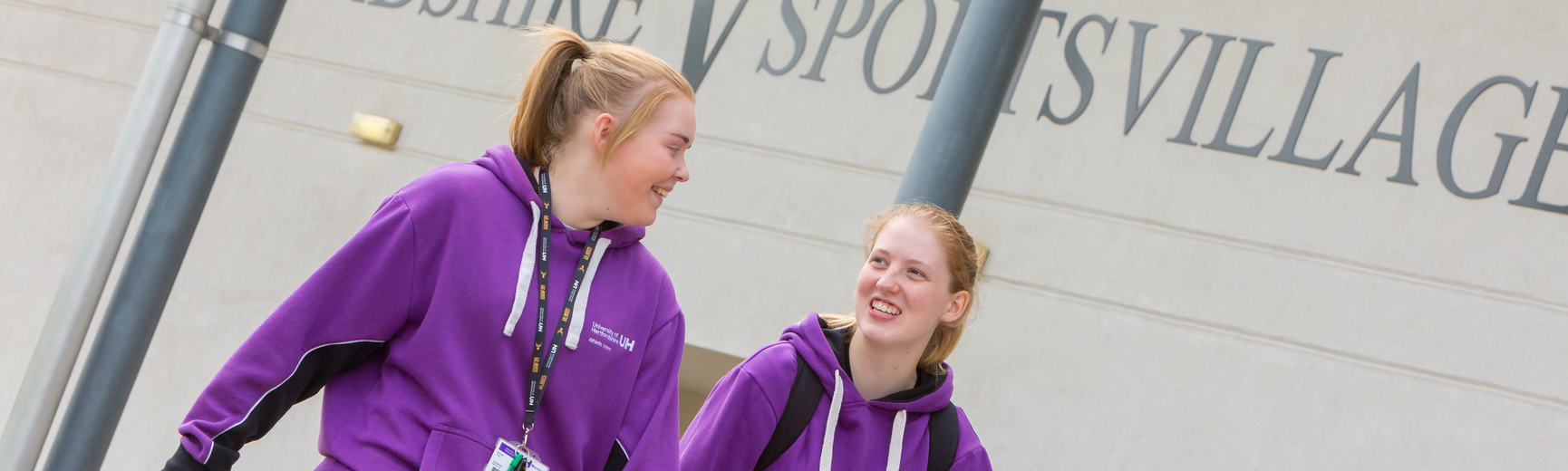 two female sport studies students walking outside the Hertfordshire Sport Village