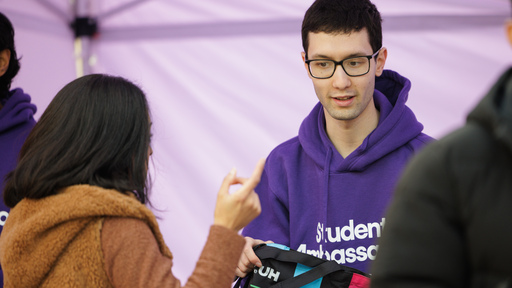 Image of a student ambassador greeting a visitor at an open day